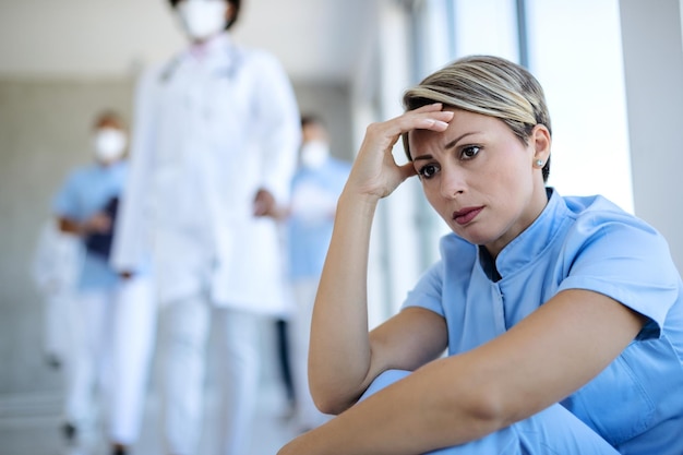 Free Photo distraught nurse sitting in a hallway and thinking of something