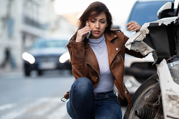 Distraught woman using mobile phone after a car accident and calling for help