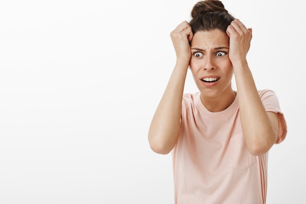 Distressed and horrified girl posing against the white wall