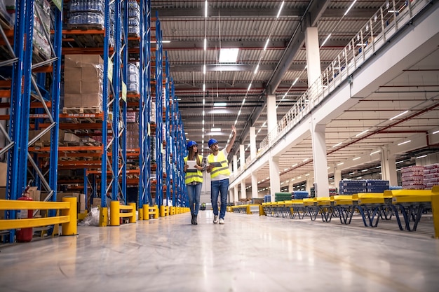 Free photo distribution warehouse interior with workers wearing hardhats and reflective jackets walking in storage area