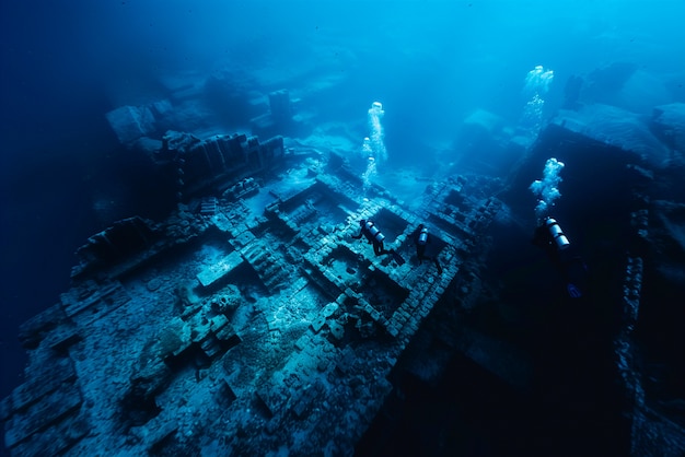 Free photo diver under the sea surrounded by archeological building ruins