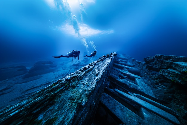 Free photo diver under the sea surrounded by archeological building ruins