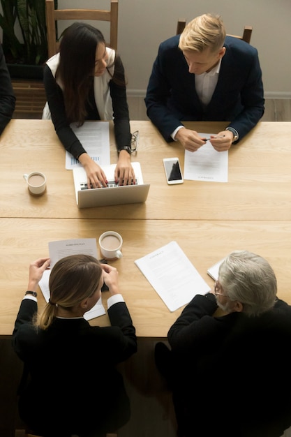 Diverse business colleagues working together at meeting, vertical top view