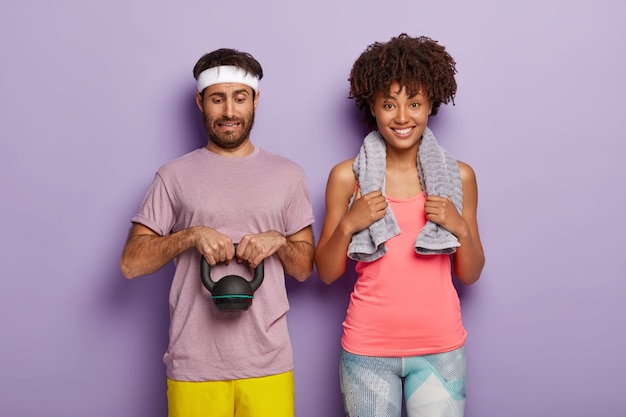 Free photo diverse couple have cardio training. handsome man lifts heavy weight