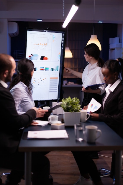 Diverse multi ethnic business teamwork overworking in office meeting room analyzing financial graphs