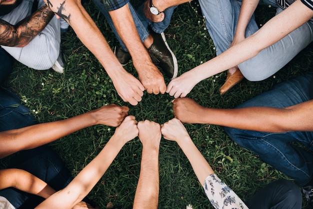 Free photo diverse people doing a fist bump in the park