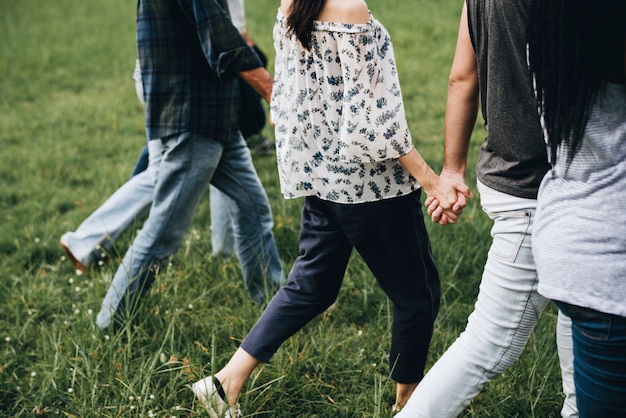 Diverse people holding hands and running in the park