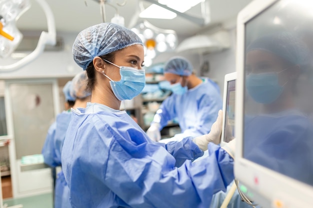 Free photo diverse team of professional surgeons performing invasive surgery on a patient in the hospital operating room nurse hands out instruments to surgeon anesthesiologist monitors vitals