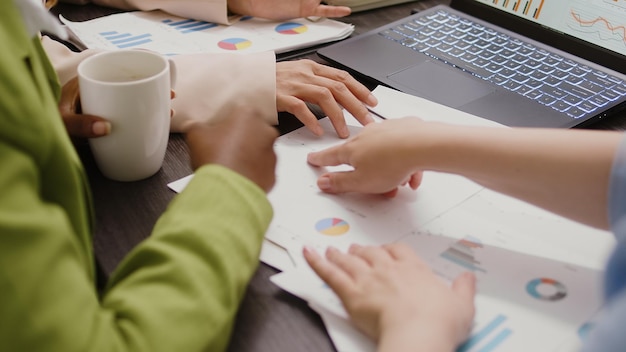 Free photo diverse women analyzing data statistics on documents, looking at papers to find new business solutions in briefing meeting boardroom. group of employees discussing marketing vision. close up.