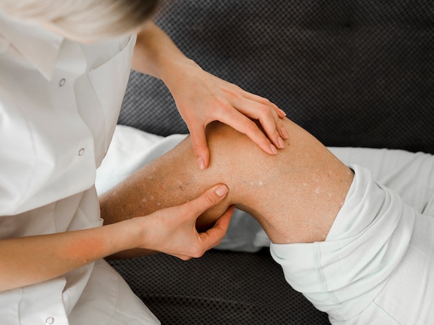 Free photo doctor checking patient's leg