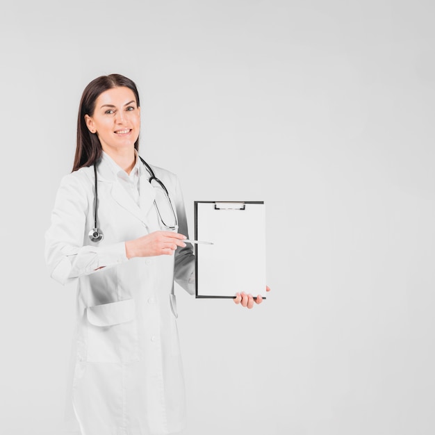 Free Photo doctor female smiling and showing on clipboard