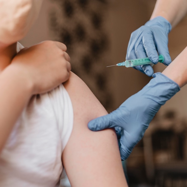 Free photo doctor giving child a vaccine while wearing gloves