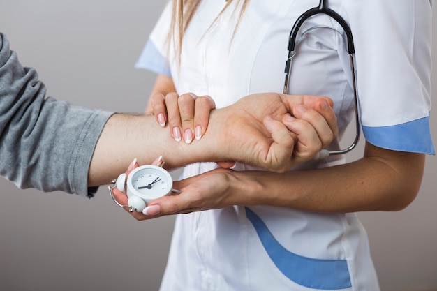 Doctor hands holding a clock and patient hand