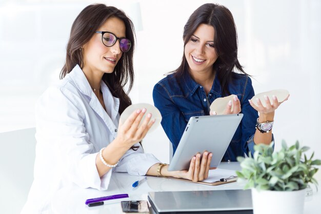 Doctor and her patient choosing mammary prosthesis in the office.