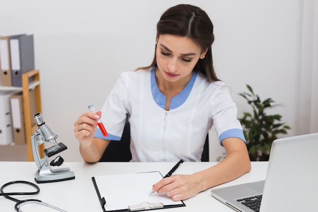 Doctor holding a blood sample and writing a report