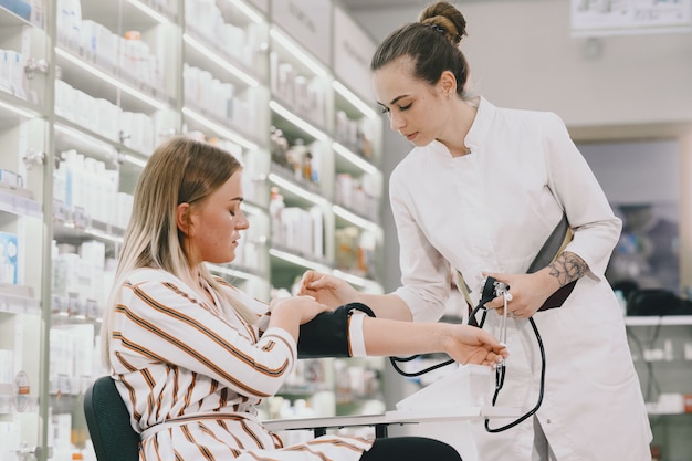 Doctor holding dial while measuring woman's pressure. Woman in a white uniform.