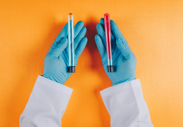 Free photo doctor holding lab vials in both hands on orange