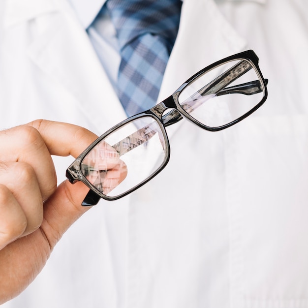 Free photo doctor holding in one hand a pair of black framed glasses