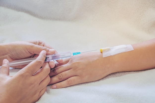 Doctor holding syringe in hand injects to a patient arm