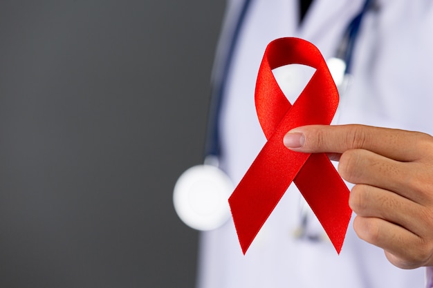 Free photo the doctor holds a red ribbon, hiv awareness awareness, world aids day and world sexual health day.