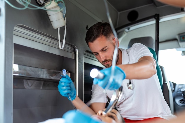 Doctor is ready for endotracheal intubation for non breathing patient Young female paramedic holding iv solution EMS Paramedics Provide Medical Help to an Injured Patient on the Way to a Hospital