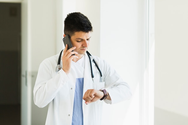 Doctor making phone call and checking time