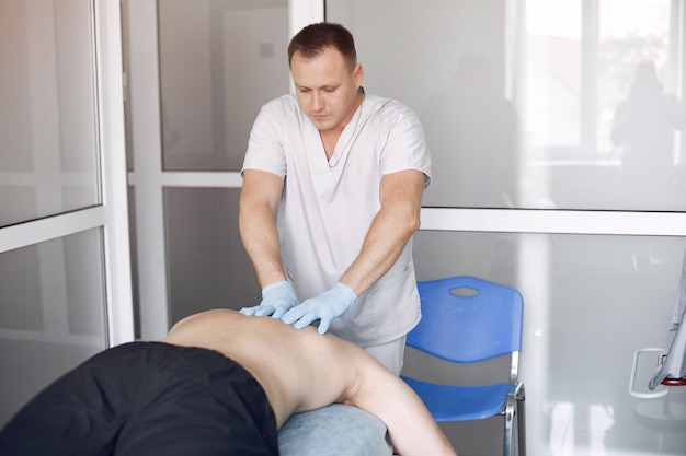 The doctor massages the man in the hospital