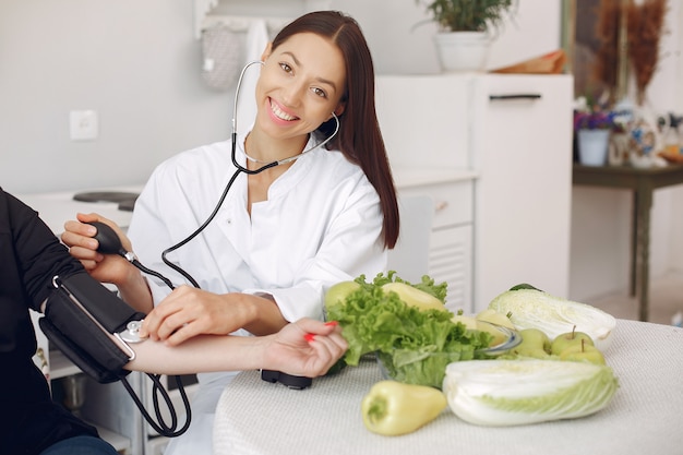 Doctor measures the pressure of the patient in the kitchen