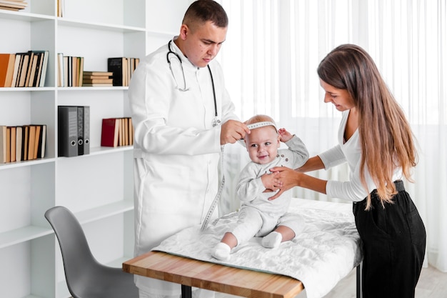 Free photo doctor measuring new born baby head