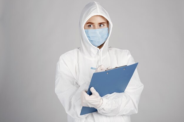 Doctor in a medical mask. Coronavirus theme. Isolated over white wall. Woman in a protective suit.