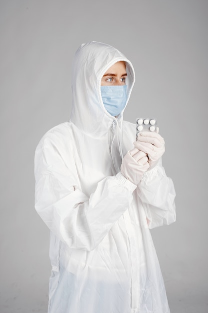 Doctor in a medical mask. Coronavirus theme. Isolated over white wall. Woman with pills.