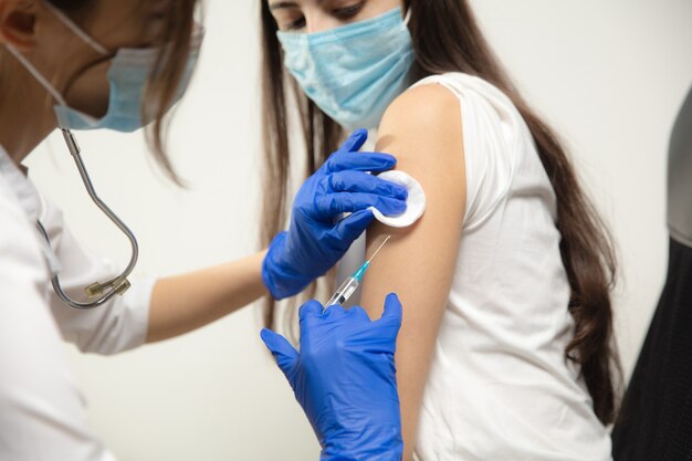 Doctor or nurse giving vaccine to patient using the syringe injected in hospital. Preparing dose in needle. Protection against coronavirus, COVID-19 pandemic and pneumonia. Healthcare, medicine.