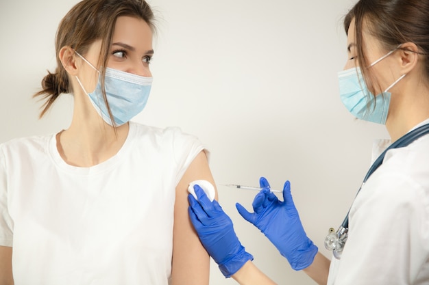 Doctor or nurse giving vaccine to patient using the syringe injected in hospital. Preparing dose in needle. Protection against coronavirus, COVID-19 pandemic and pneumonia. Healthcare, medicine.