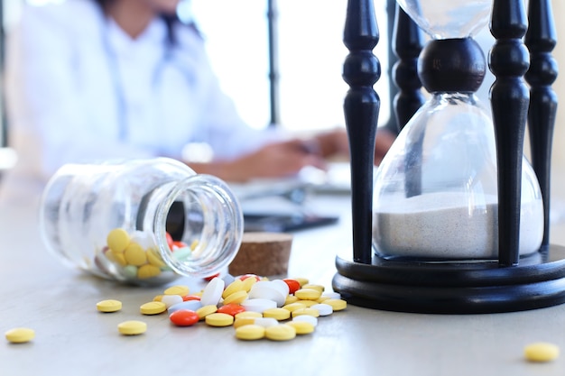 Free photo doctor at the office with pills and hourglass