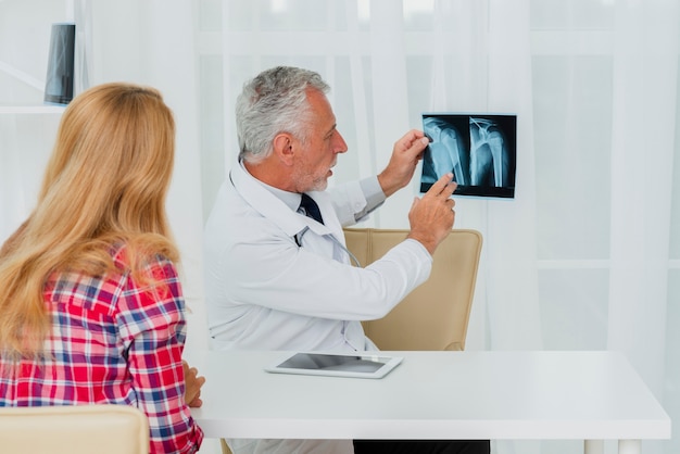 Doctor pointing at x-ray with patient