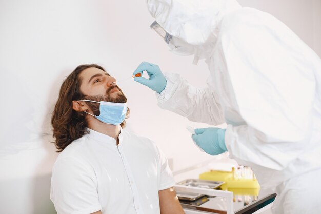 Doctor protective suit and surgical face mask. Cotton swab from the throat and nose of the patient's. Coronavirus test, test for covid-19 infection in a pandemic.