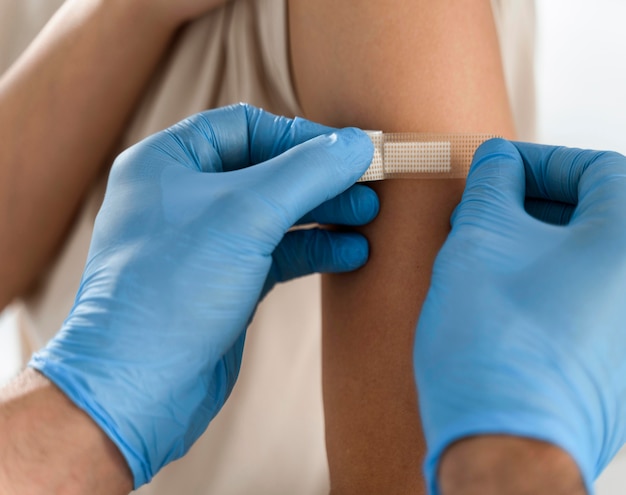 Free Photo doctor putting a bandage on a patient's arm