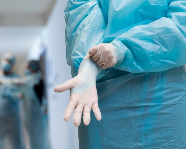 Free photo doctor putting on surgical gloves close-up