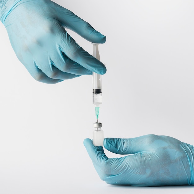 Free photo doctor putting a vaccine in a syringe