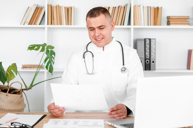 Free photo doctor sitting on desk and looking on a sheet