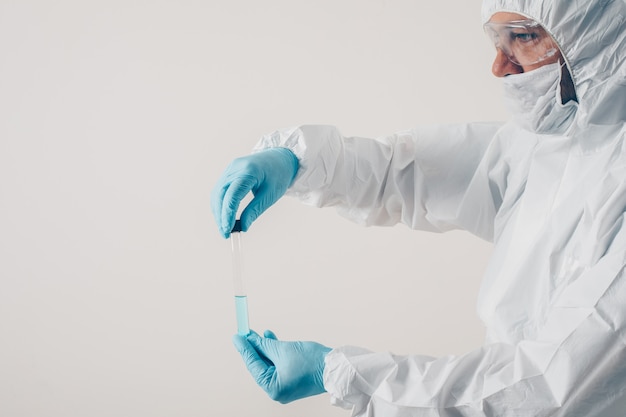 A doctor standing and holding medicine in light background in medical gloves and protective suit .  