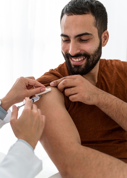 Doctor vaccinating a handsome bearded man