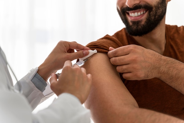 Free Photo doctor vaccinating a smiley man