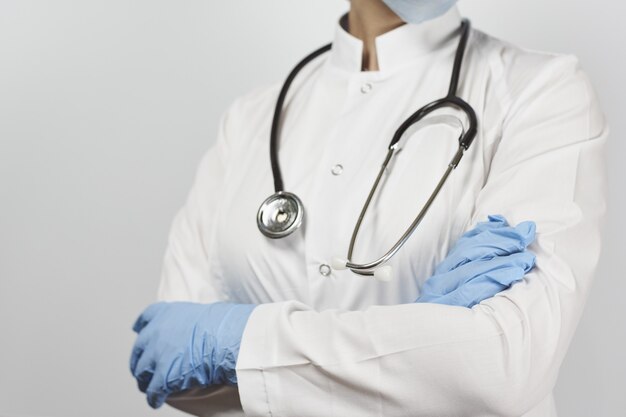 Doctor in a white uniform with stethoscope standing with crossed arms