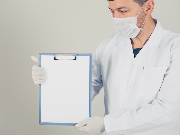 Free photo doctor with gloves looking and holding paper holder vertically. side view.