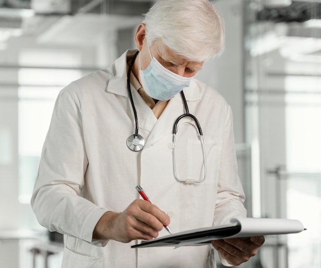 Free photo doctor with medical mask checking his notes