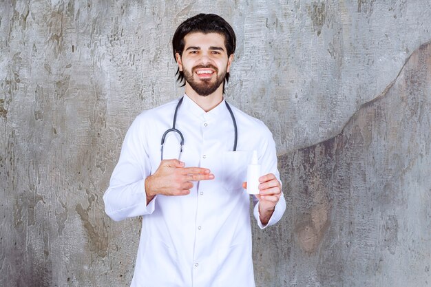 Doctor with a stethoscope holding a white tube of hand sanitizer spray. 