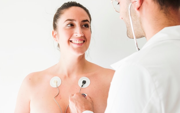 Free photo doctor with stethoscope near woman with electrodes