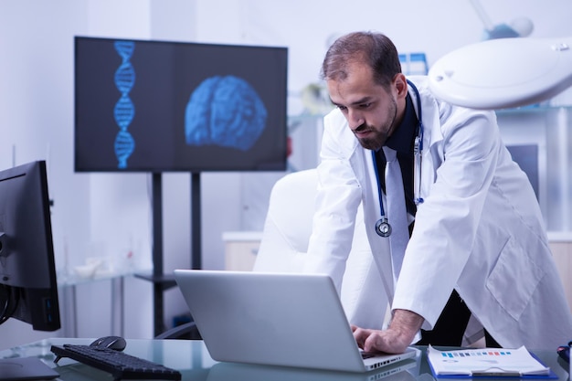 Free photo doctor working on laptop with brain image in the background. cardiologist doctor at work.