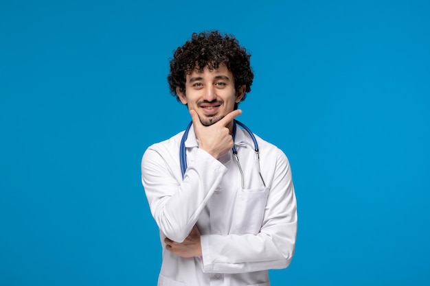 Doctors day curly handsome cute guy in medical uniform thinking happily